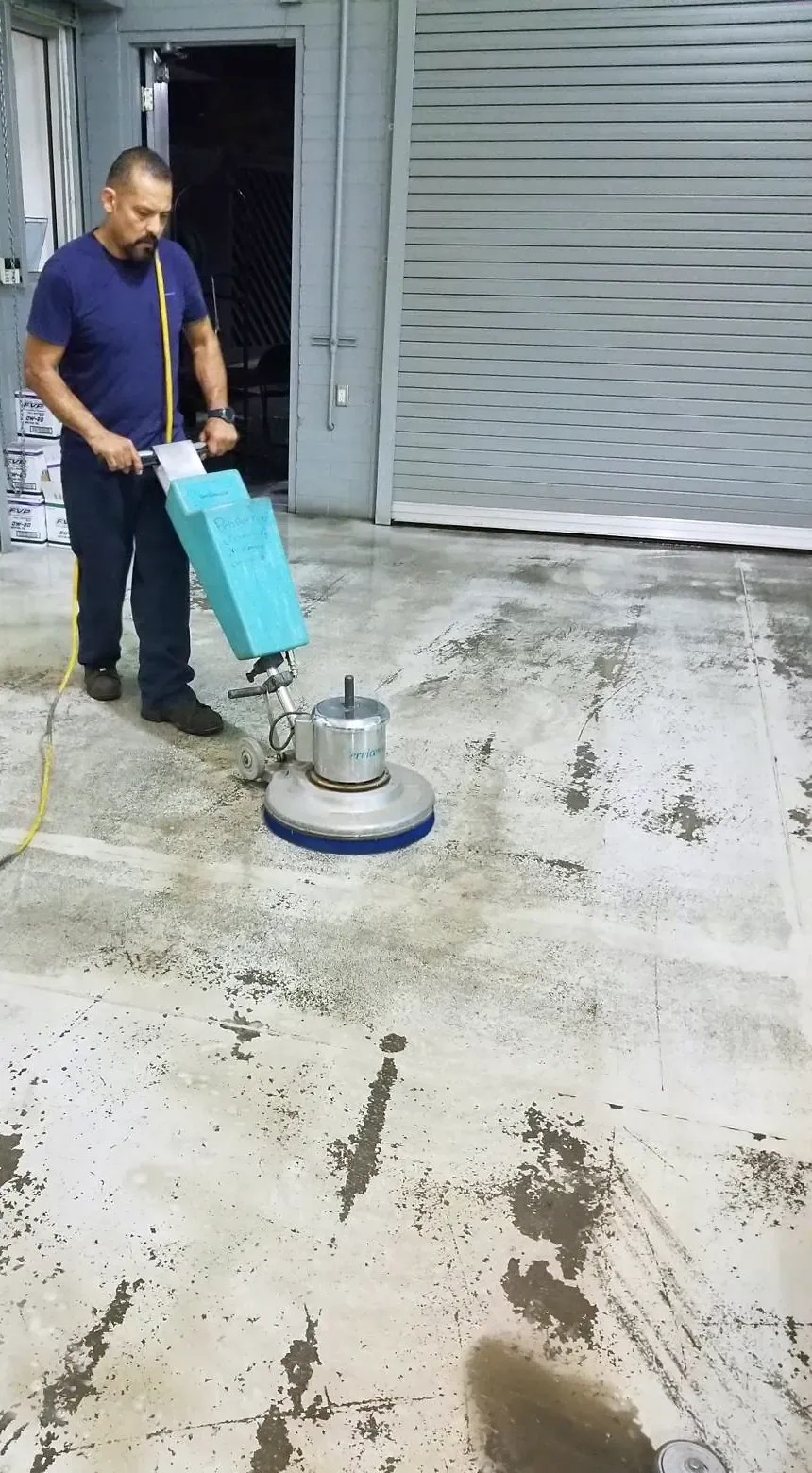 Floor technician running a buffer on a concrete shop floor
